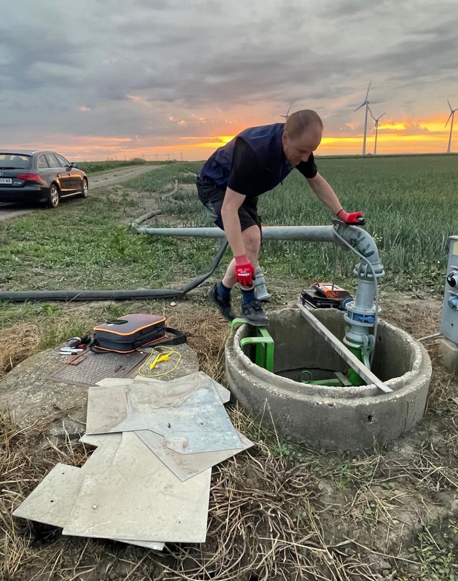 Elektrotechniker von Anmayr Elektrotechnik wartet eine Pumpenanlage im Feld bei Sonnenuntergang